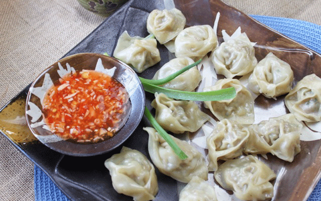 steamed Chinese shumai shrimp and turkey sausage dumplings on a brown square plate with a side of sweet chili dipping sauce