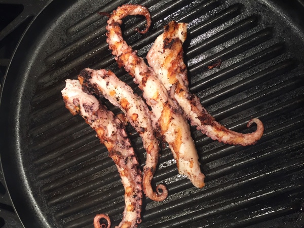 Octopus tentacles being grilled on a grill pan.