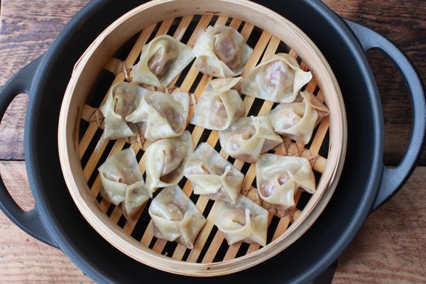 wontons in a steamer basket on top of a wok