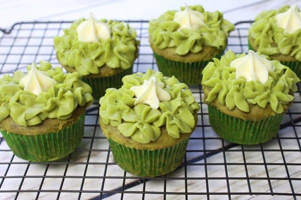 Matcha green tea cupcakes with green frosting on a cooling rack.