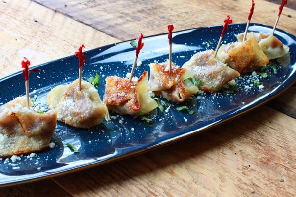 savory pumpkin wonton bites on a blue serving platter on top of a wooden board.