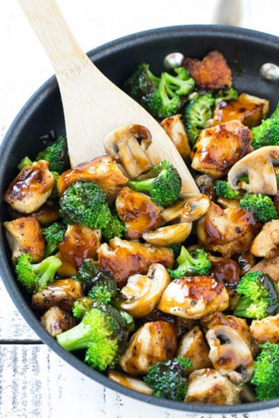 chicken and broccoli stir fry in a wok with a wooden spatula