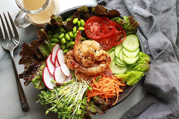 miso shrimp salad with fresh vegetables in a bowl on a gray napkin