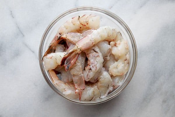 raw shrimp in a glass bowl on top of a marble board