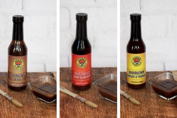 Three bottles of Korean sauces placed on top of a wooden board with a basting brush on the side