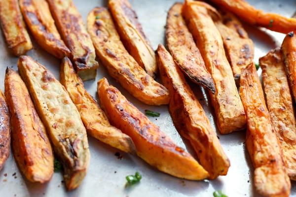 Sweet potato fries with sriracha seasoning on a baking sheet right out of the oven.