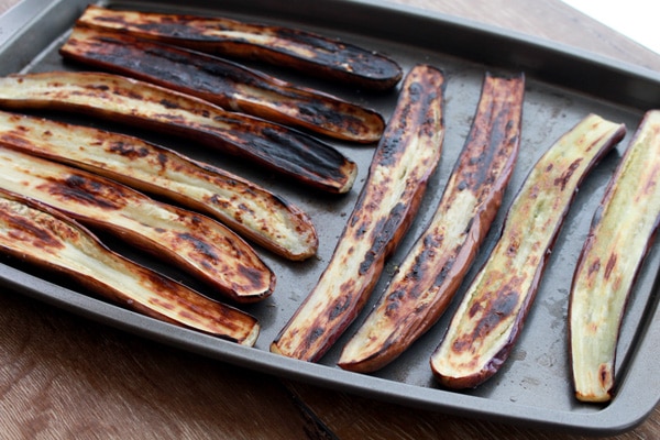Charred Chinese eggplant cut in half on baking tray right out of the oven.