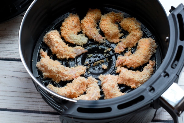breaded shrimp in an air fryer basket.
