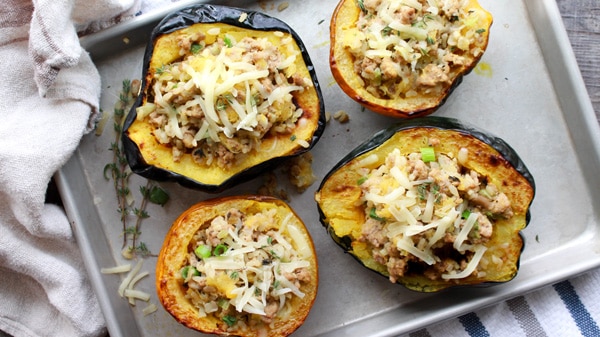 stuffed roasted acorn squash with ground turkey and rice on a baking tray.