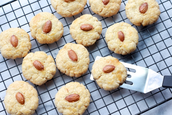 Chinese almond cookies on a cooling rack right out of the oven with a small spatula.