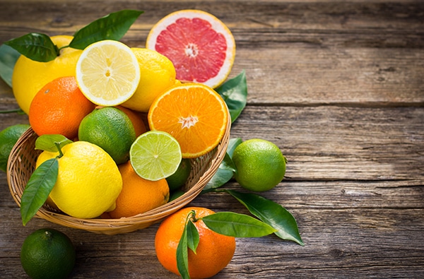 fresh and juicy citrus fruits in a basket on a rustic wooden table