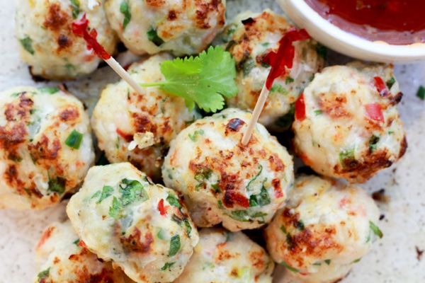 spicy baked shrimp balls piled hight with party toothpicks and a side of sweet chili sauce