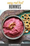 red beet hummus in a bowl with a side of pretzels for dipping