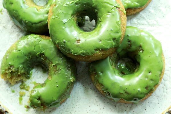 green frosted matcha donuts stacked on a white plate