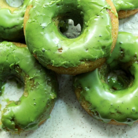 Green matcha donuts stacked on a white plate