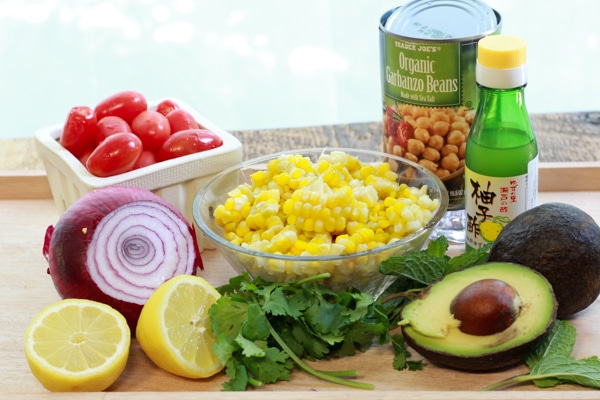 ingredients for making a corn and avocado salad on top of a wooden board
