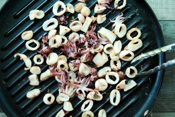 calamari rings and pieces searing on a grill pan