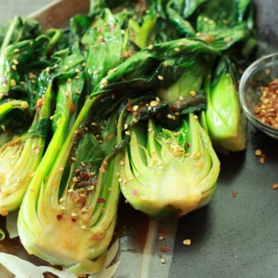 stir-fried baby bok choy on a serving plate sprinkled with red pepper flakes