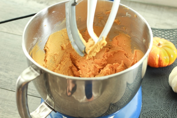 pumpkin cookie batter in a silver mixing bowl on top of a wooden board