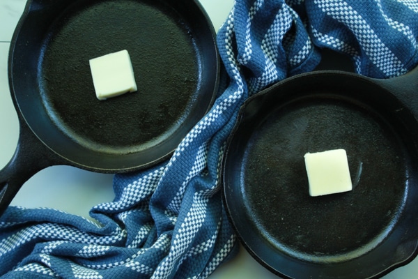 pats of butter in mini cast iron skillets on a blue napkin