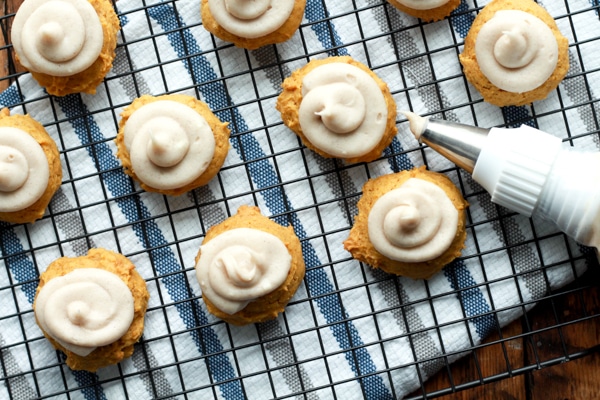 decorating pumpkin spice cookies topped with cream cheese frosting on a baking rack