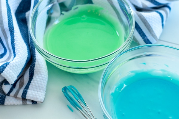 green and blue sugar cookie icing in glass bowls
