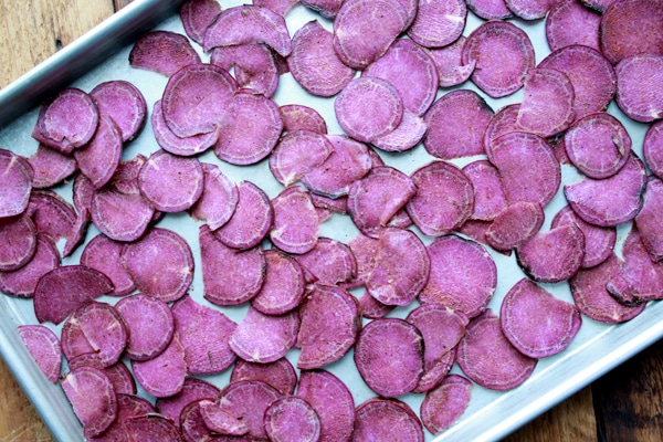 slices of purple sweet potatoes on a large baking sheet ready for the oven