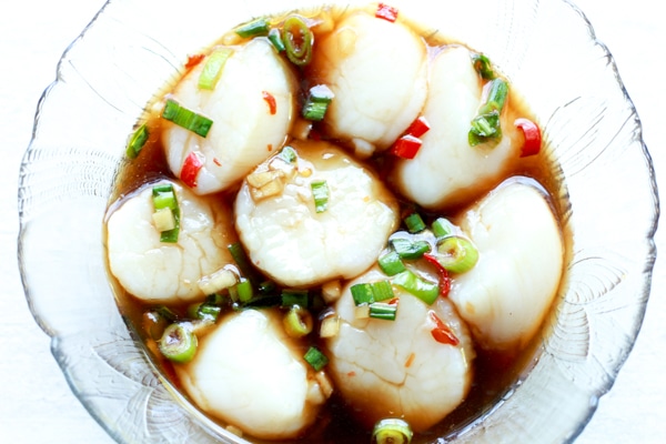 sea scallops marinating in a clear glass bowl