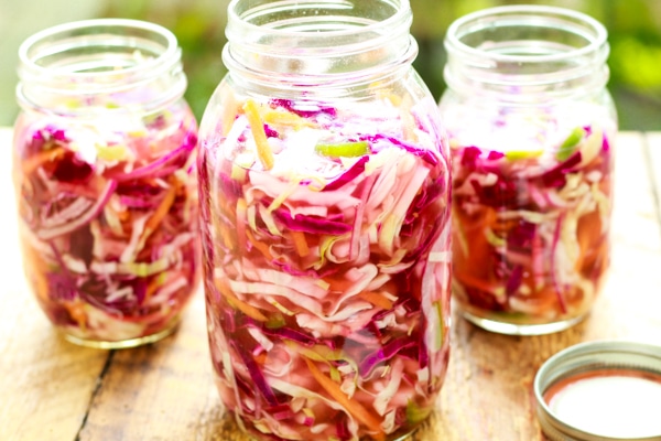 pickled veggies in three canning jars on a wooden board