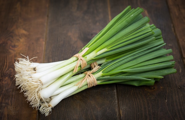 green onions bundled together on a wooden board