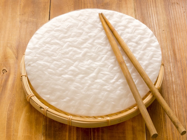 rice paper wrappers on a wooden board with chopsticks on top