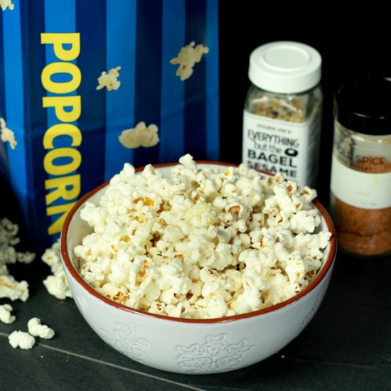 popcorn in a white bowl with two seasonings behind