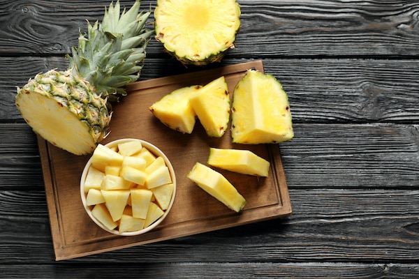 fresh pineapple sliced and chunked on a wooden board