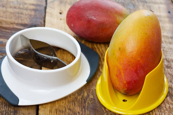 fresh mango in a mango cutter on a wooden board