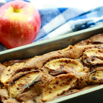 apple ginger bread in a loaf pan with red apples in the background