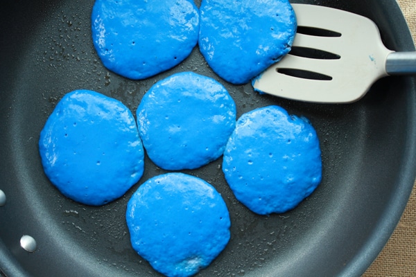 blue pancakes in a frying pan with a spatula