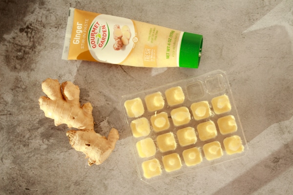 three ginger options on a board including ginger paste, fresh ginger bulb, and frozen ginger cubes