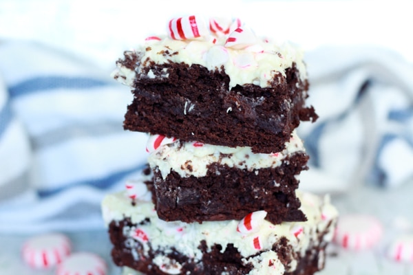 A stack of peppermint brownies with peppermint candies on top and along side