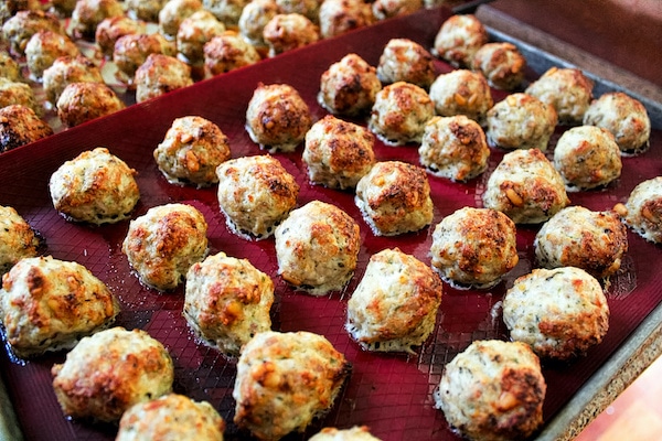 baked meatballs on a red silicon mat on top of a baking sheet