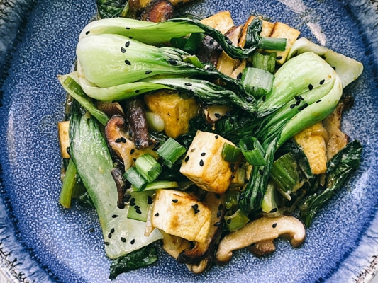 Stir-fry miso shiitake mushrooms, tofu, and baby bok choy on a blue plate.