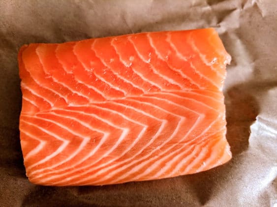 perfect marbled sushi-grade filet of salmon on a piece of brown parchment paper
