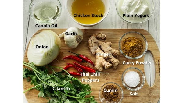 Ingredients for making Thai Curry Chicken on a wooden cutting board.