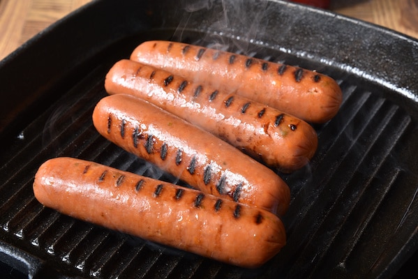 Grilling four hot dogs on a cast iron grill