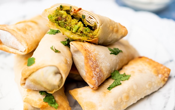 Vegan Avocado Egg Rolls stacked on top of a white plate.