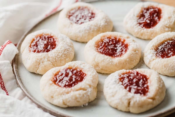 A plateful of festive sourdough thumbprint cookies with a white napkin on the side.