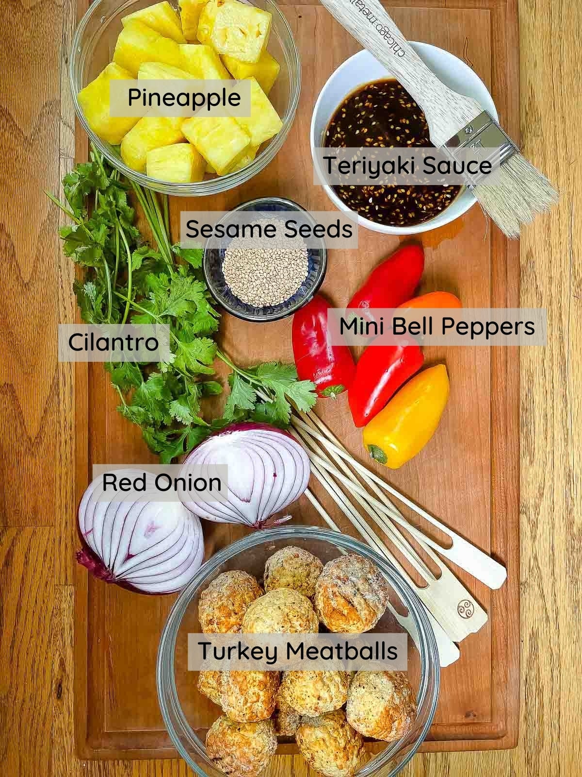 Several ingredients on a wooden board for making turkey meatball skewers.