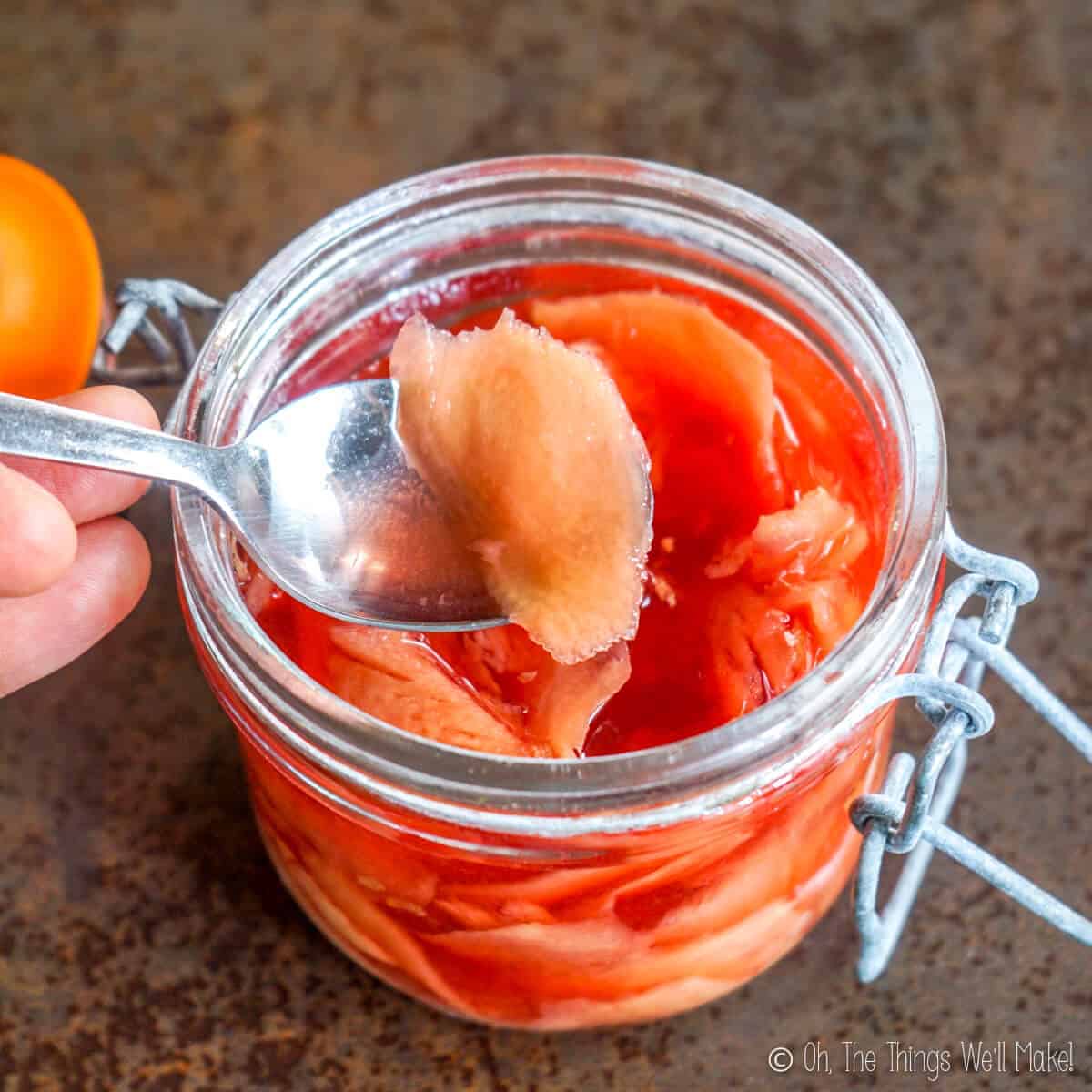 Homemade pickled ginger for sushi in a small canning jar with a spoon inserted.