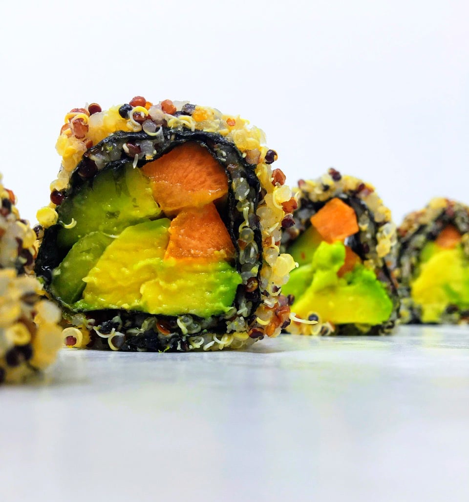 A sliced healthy quinoa sushi roll on a white surface.