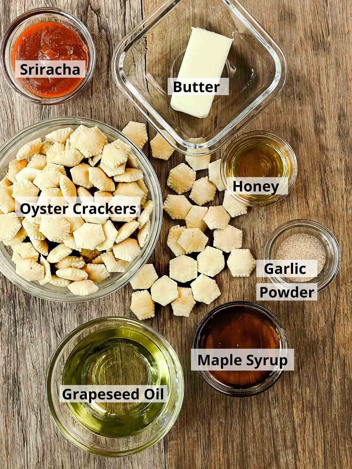 Labeled ingredients in glass bowls for making spicy baked sriracha oyster crackers.