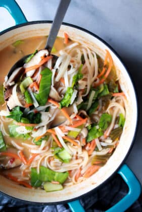 miso chicken noodle soup in a blue cast iron pot with a silver spoon inserted.